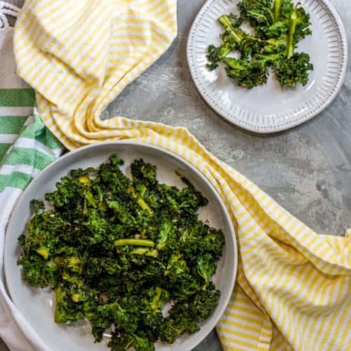 air fryer kale chips in serving dish with small plate of some off the side behind it