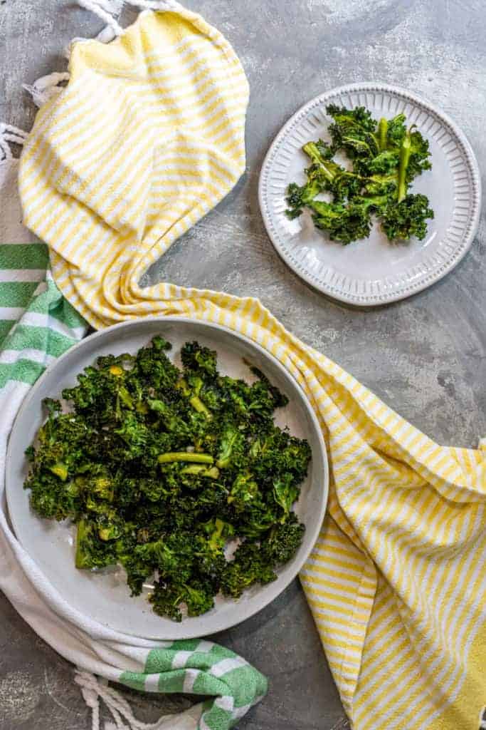 air fryer kale chips in serving dish with small plate of some off the side behind it
