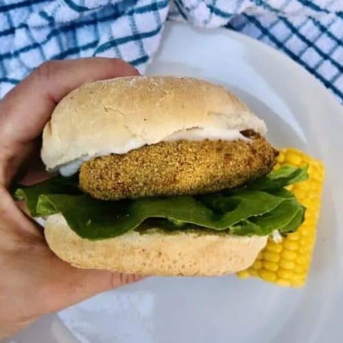 hand holding vegan chicken sandwich on a bun with lettuce and vegan mayo