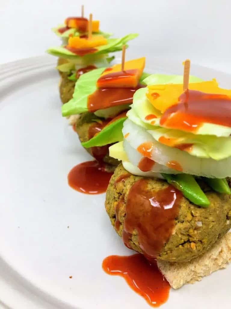 lentil sliders topped with avocado, onion, lettuce and vegan cheese
