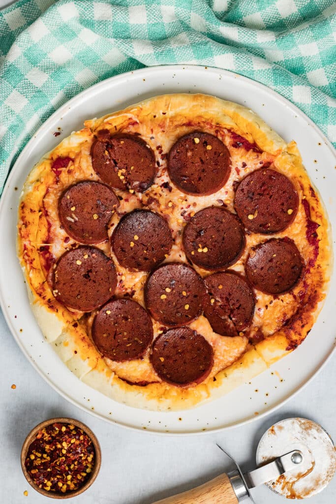 overhead of vegan pepperoni pizza topped with crushed red pepper