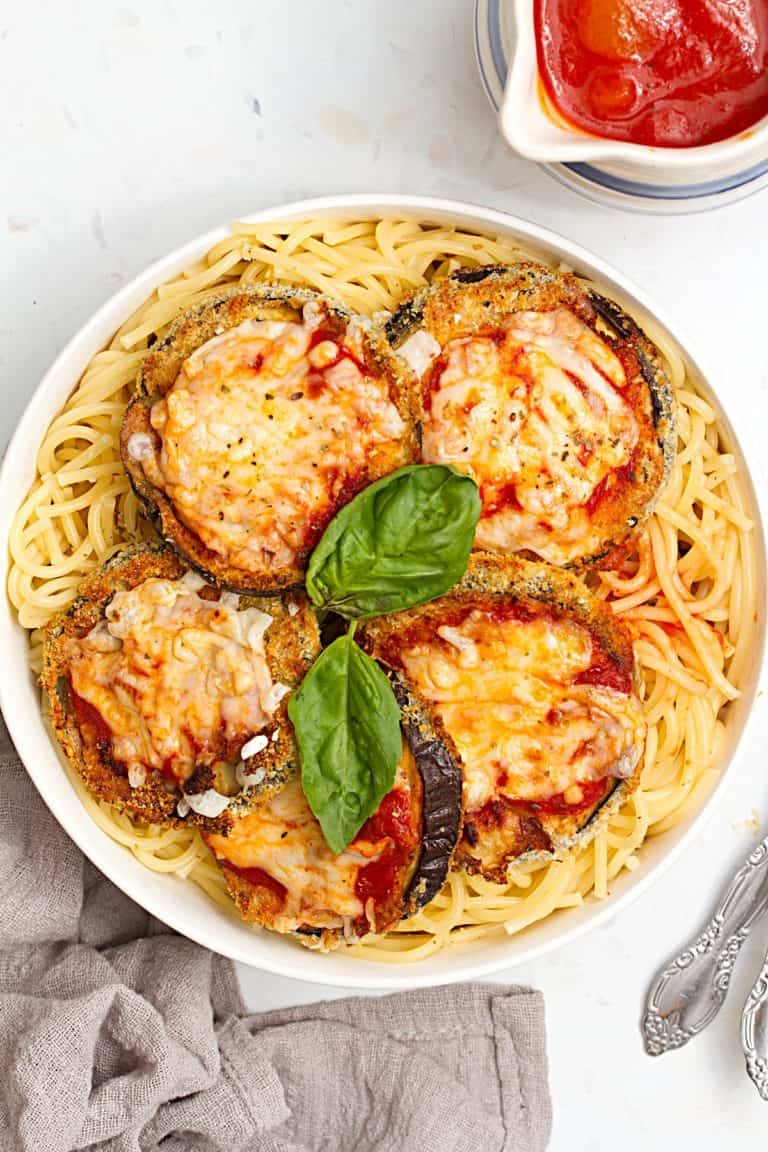 overhead of vegan eggplant Parmesan over top of spaghetti in white bowl