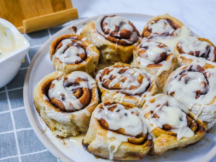 cinnamon rolls topped with icing on a white plate