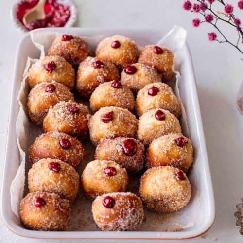 air fryer doughnuts in a serving dish with a bowl of jam in the background