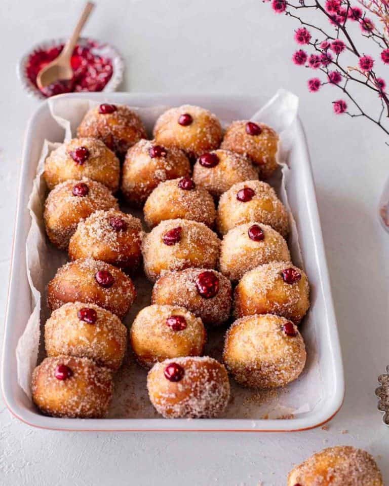 air fryer doughnuts in a serving dish with a bowl of jam in the background