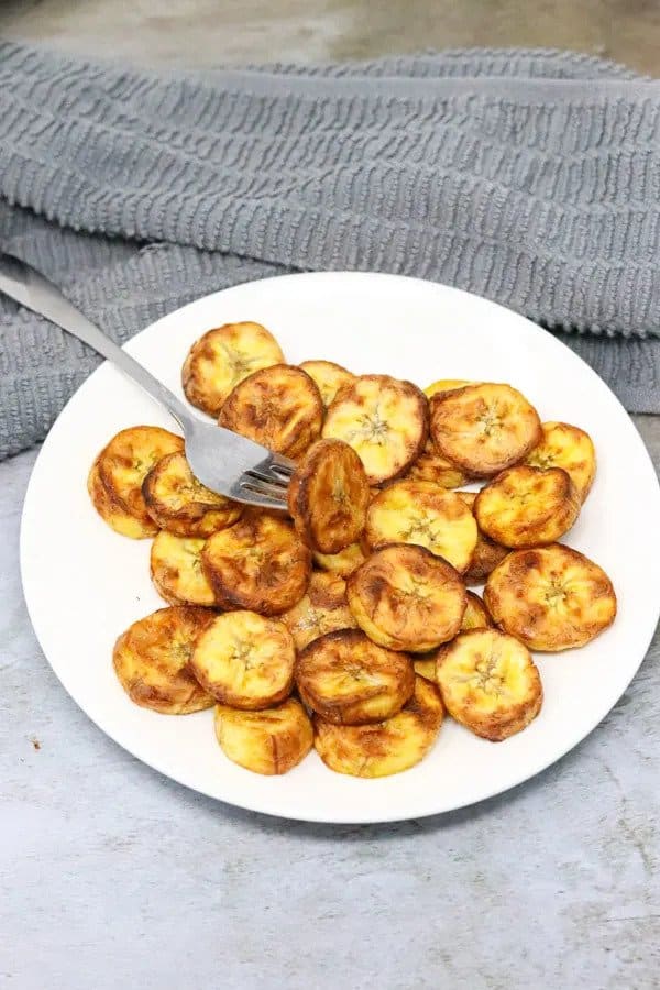 air fryer sweet plantains on white plate with a fork in one of them