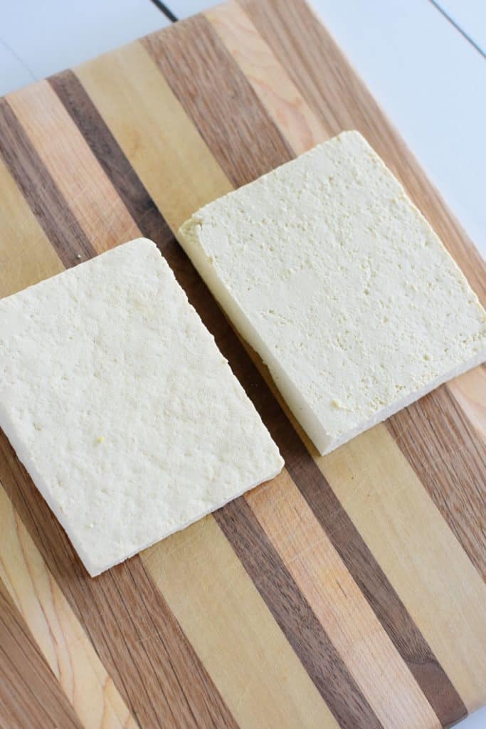 tofu block sliced in half lengthwise on wooden board