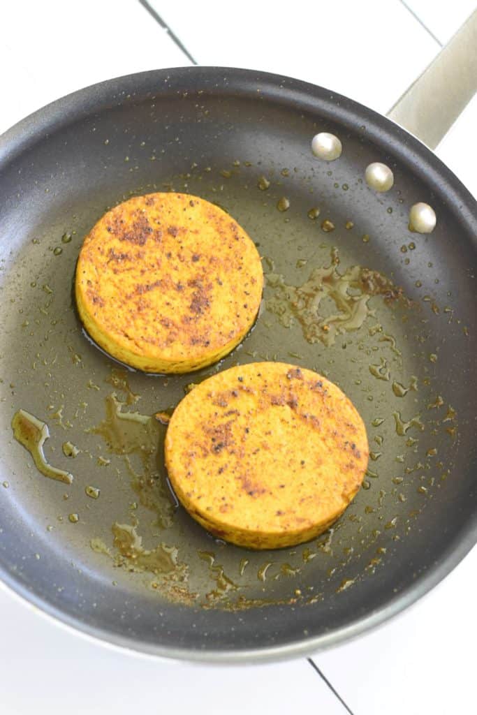 tofu circles frying in non-stick pan in olive oil