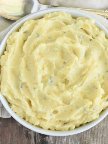 close-up overhead of mashed potatoes in white bowl with spoon behind it