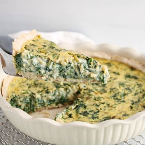 pulling out a slice of vegan spinach quiche from the pie plate