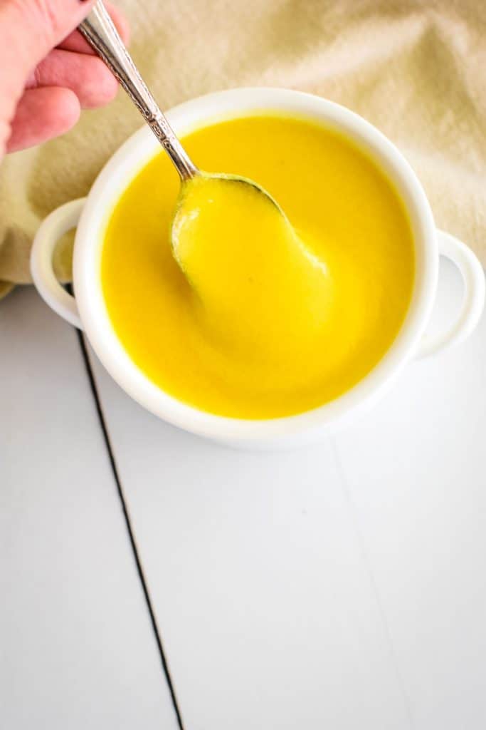scooping up a spoonful of hollandaise from a white serving bowl
