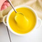 taking a spoonful of hollandaise from white bowl