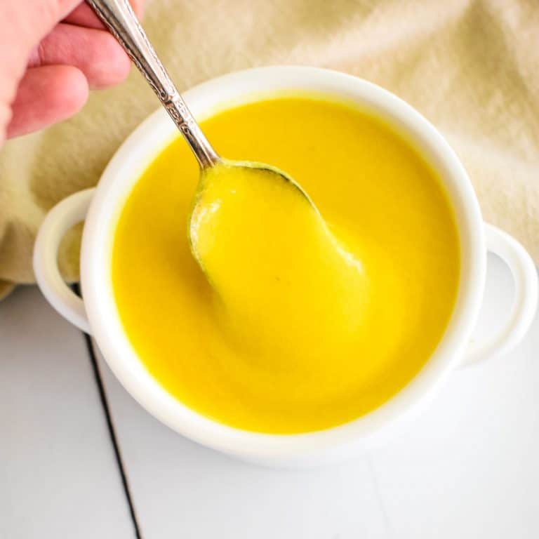 taking a spoonful of hollandaise from white bowl