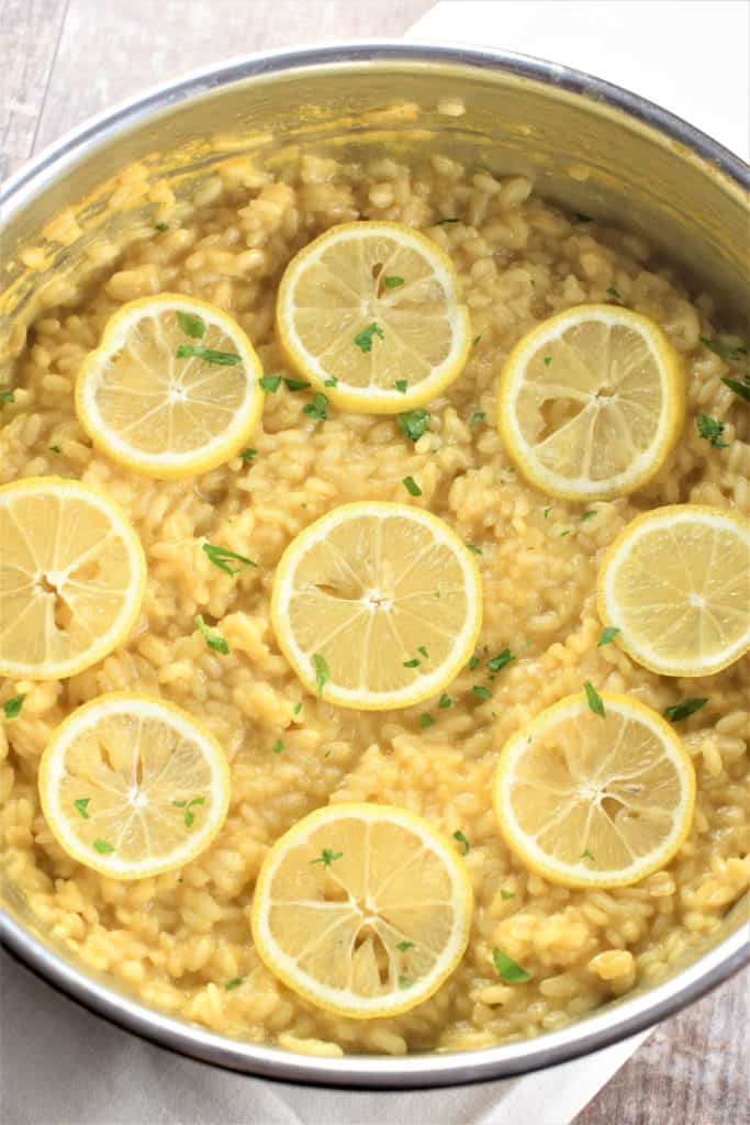 close-up overhead of risotto in the pan garnished with lemon slices