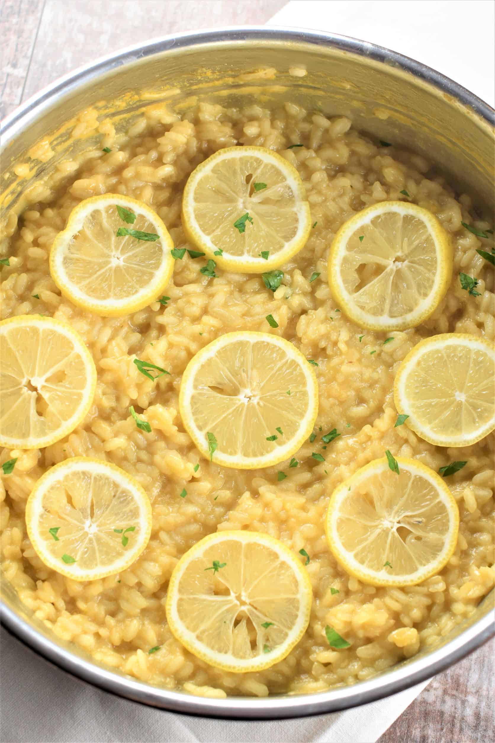 close-up overhead of risotto in the pan garnished with lemon slices
