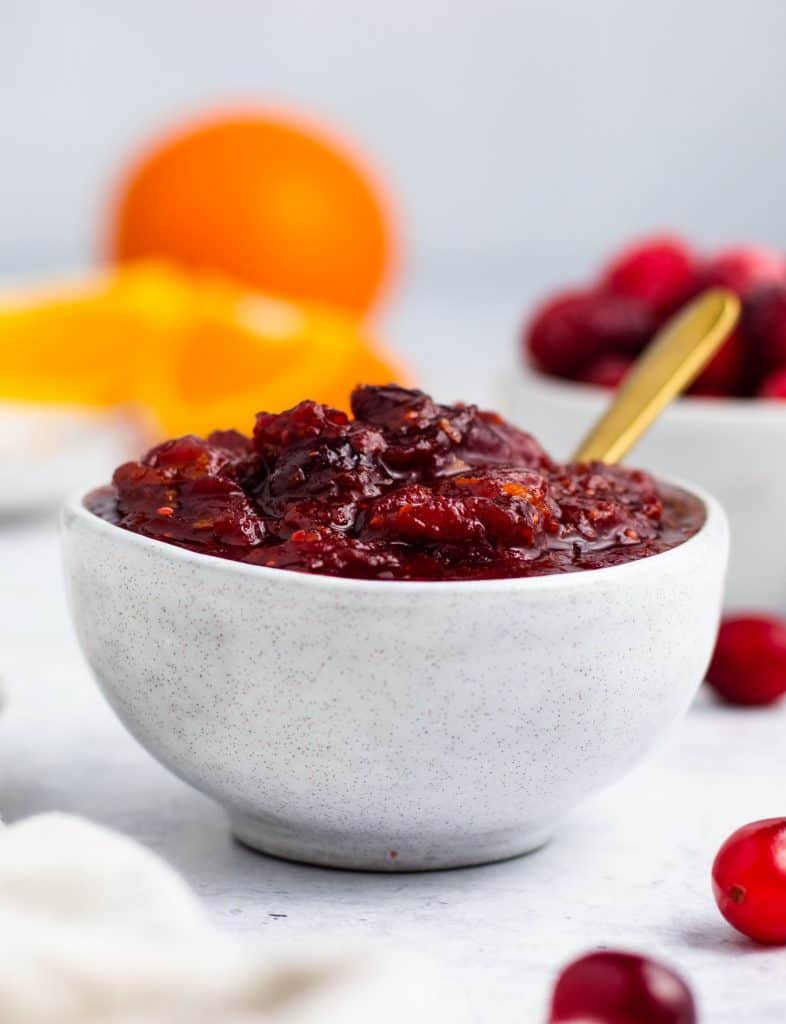 front view of cranberry sauce in serving bowl with spoon in it