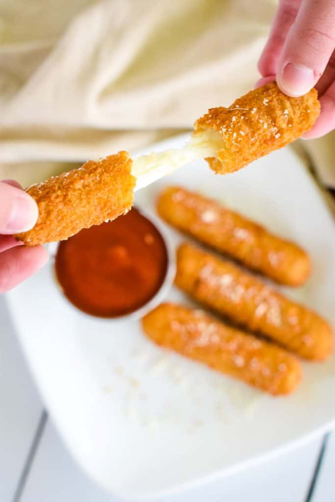 pulling two ends of a mozzarella stick to show the cheese