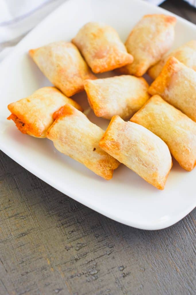 front view of gluten free pizza rolls on white plate.