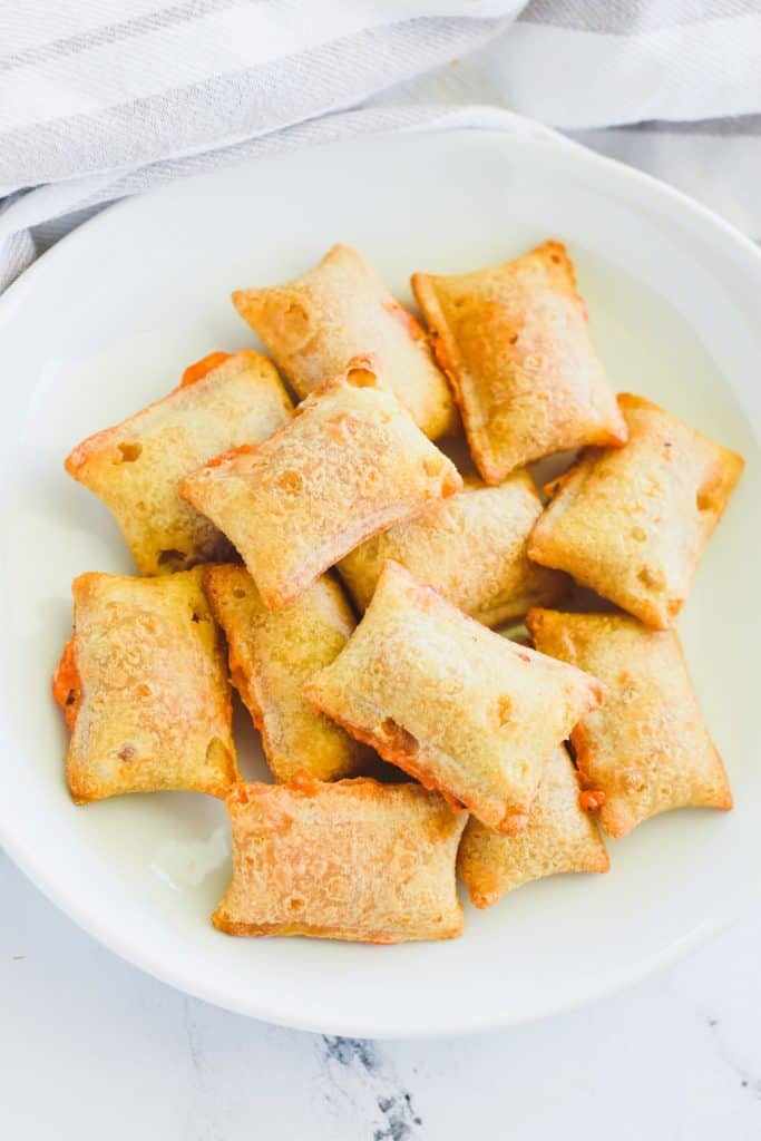 overhead of pizza rolls piled on each other on a white plate.