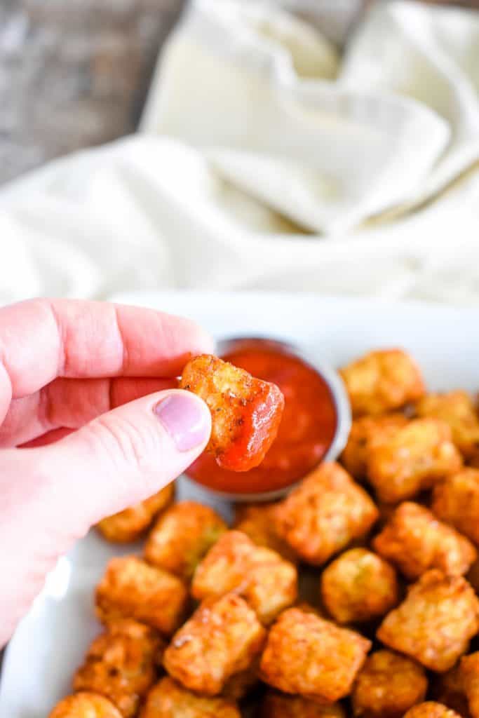 holding potato puff with ketchup on it