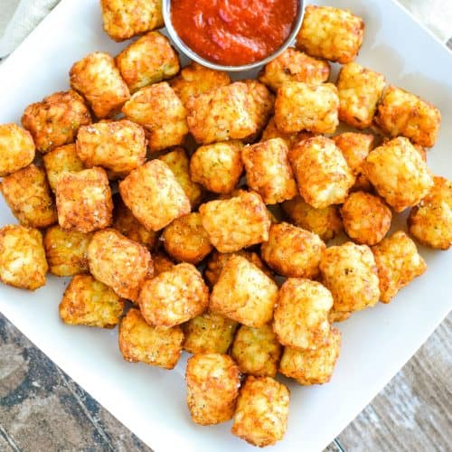 Overhead of Tater Tots on white square plate with ketchup side