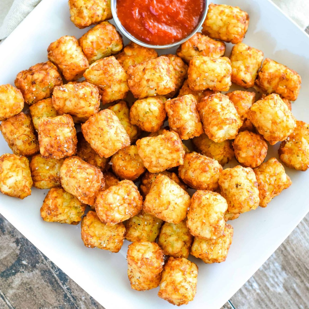 overhead of tater tots on white square plate with side of ketchup