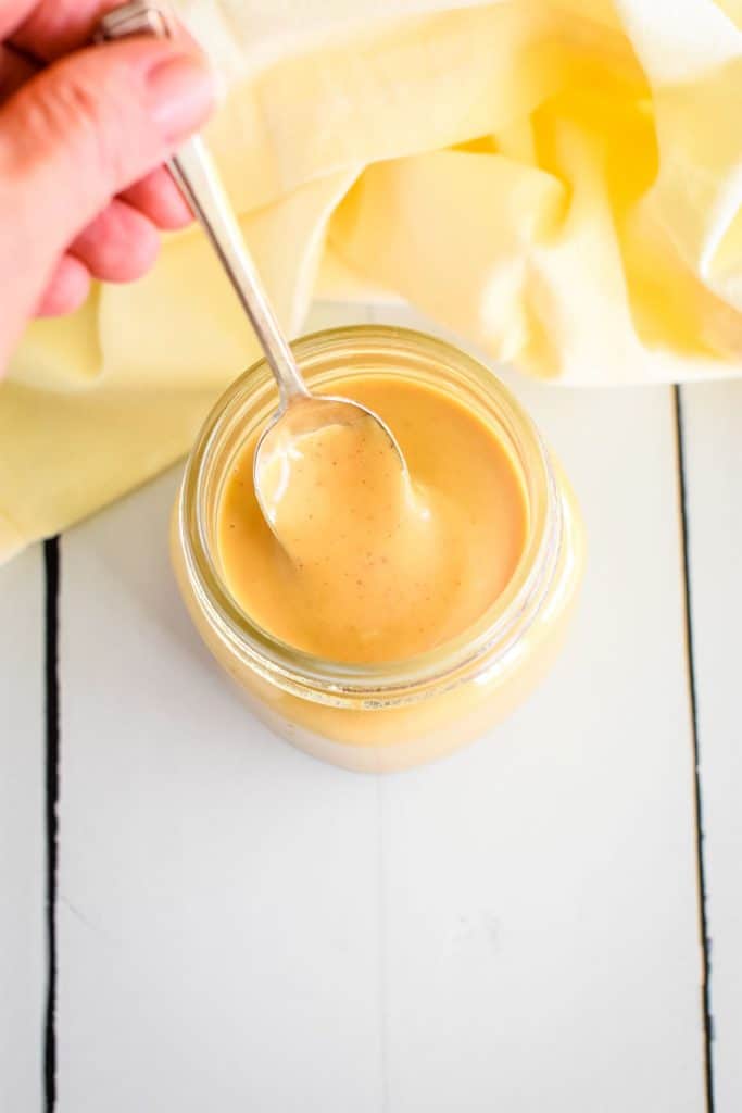 overhead holding spoon in dipping sauce in mason jar