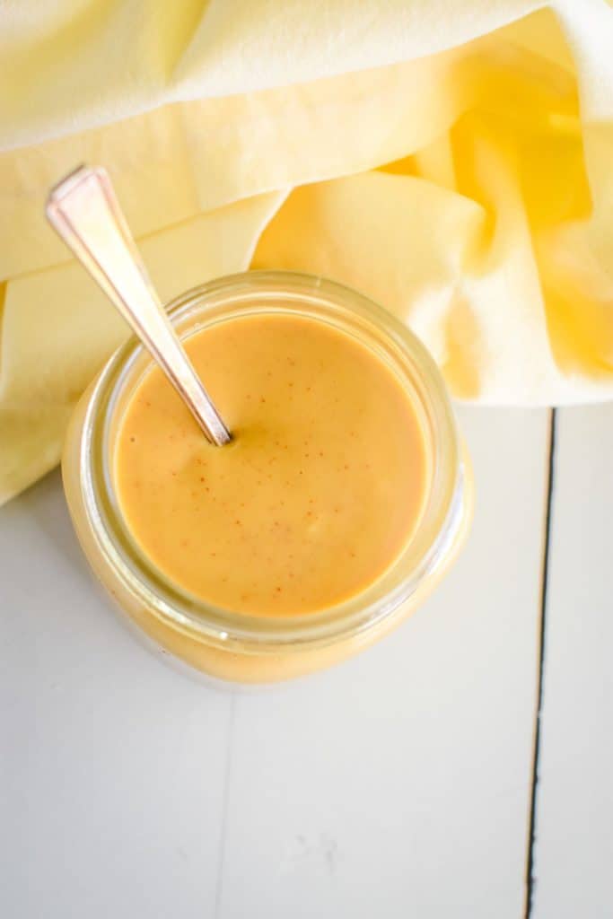 overhead of maple mustard dipping sauce in mason jar with spoon in it