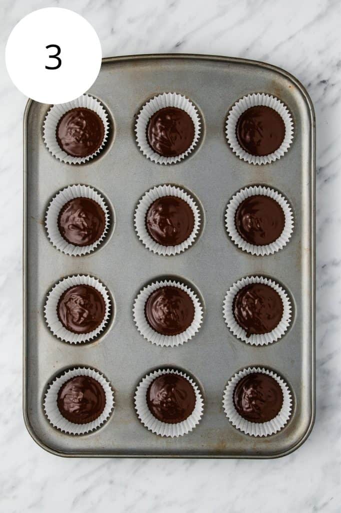 first layer of chocolate in cupcake liners in cupcake pan