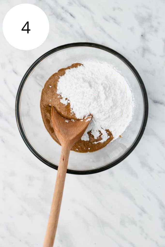 peanut butter and powdered sugar in mixing bowl with wooden spoon before mixing