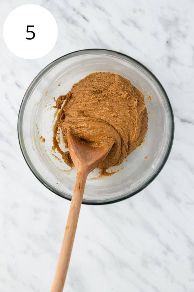 peanut butter combined with powdered sugar in mixing bowl with wooden spoon