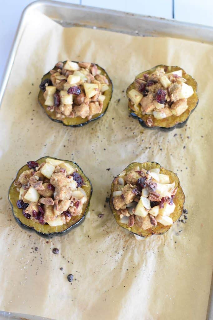 4 acorn squash halves with stuffing after roasting in oven on parchment-lined baking sheet
