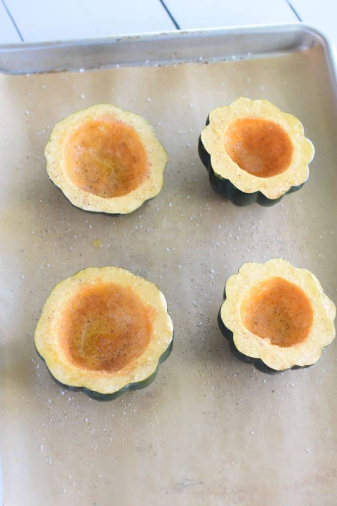 4 acorn squash halves with olive oil, salt and pepper on parchment-lined baking sheet