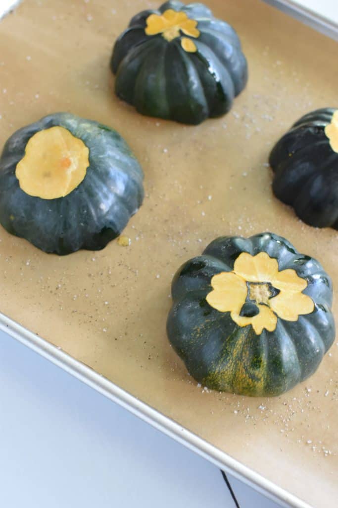 4 acorn squash halves flipped over to be face down on parchment-lined baking sheet