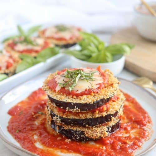 stack of eggplant parm on a white plate lined with sauce