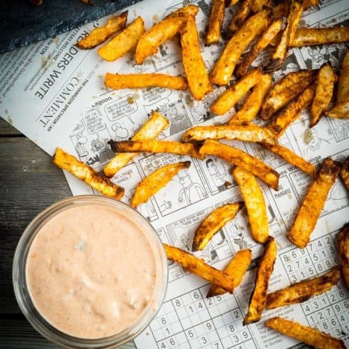 overhead of turnip fries on newspaper with side of dipping sauce