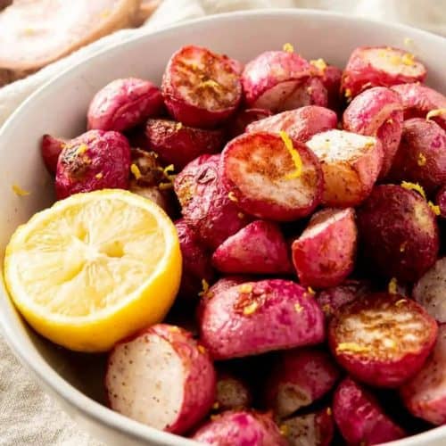 roasted radishes in white bowl with a half of a lemon