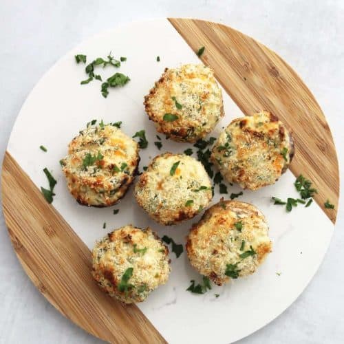 overhead of stuffed mushrooms on circular serving board garnished with parsley