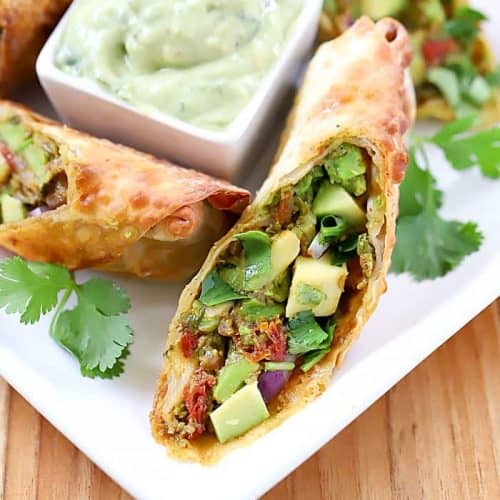 avocado southwest egg rolls on a white dish with dipping sauce in the center