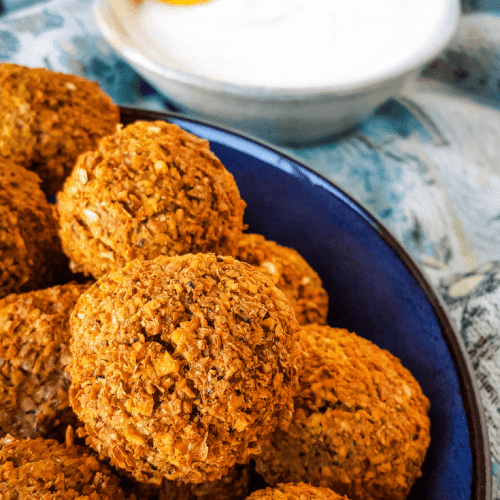 falafel in blue bowl with tahini sauce off to the side