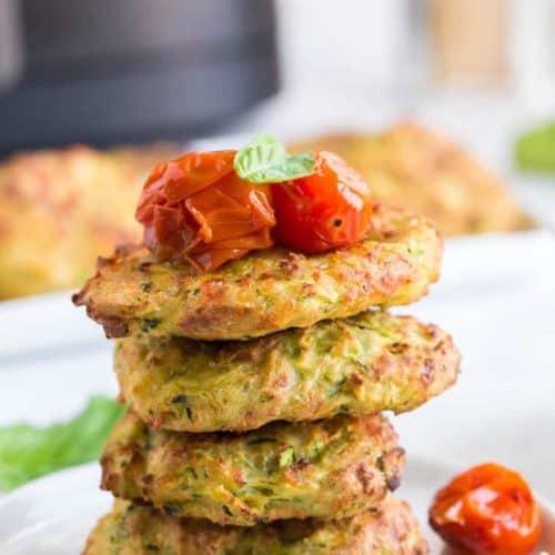 stack of 4 zucchini fritters with roasted tomatoes and basil garnish
