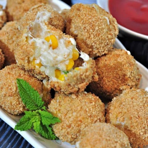 corn cheese balls on serving platter with one opened up on the top