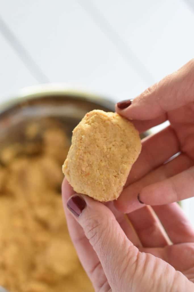 holding up a shaped nugget over the chickpea mixture
