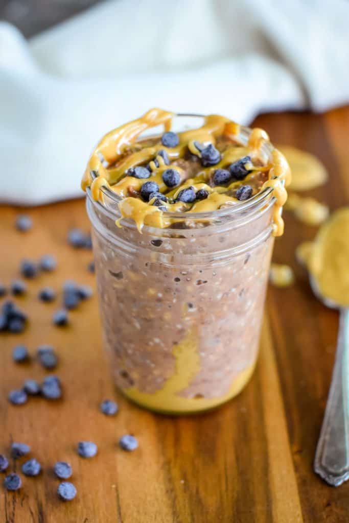 chocolate peanut butter overnight oats in a mason jar with extra peanut butter and chips on top