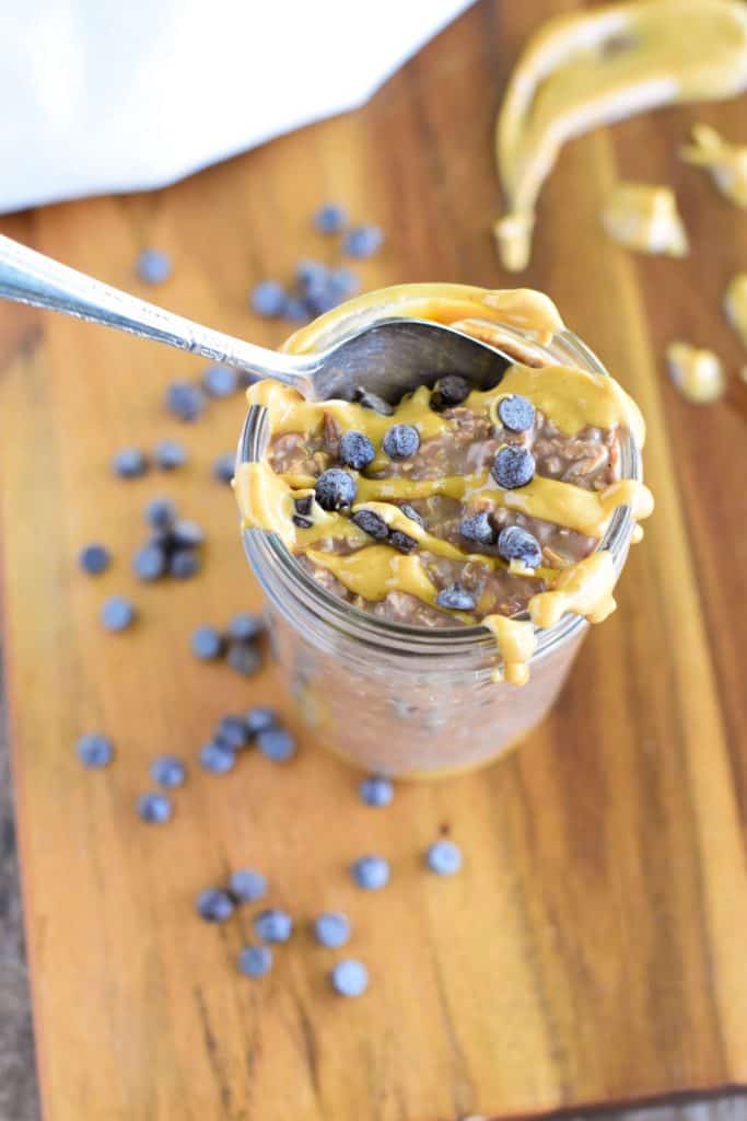 overhead of oats in a mason jar topped with extra peanut butter and chips and a spoon going into it