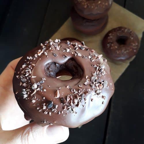 hand holding vegan chocolate doughnut for a close-up.