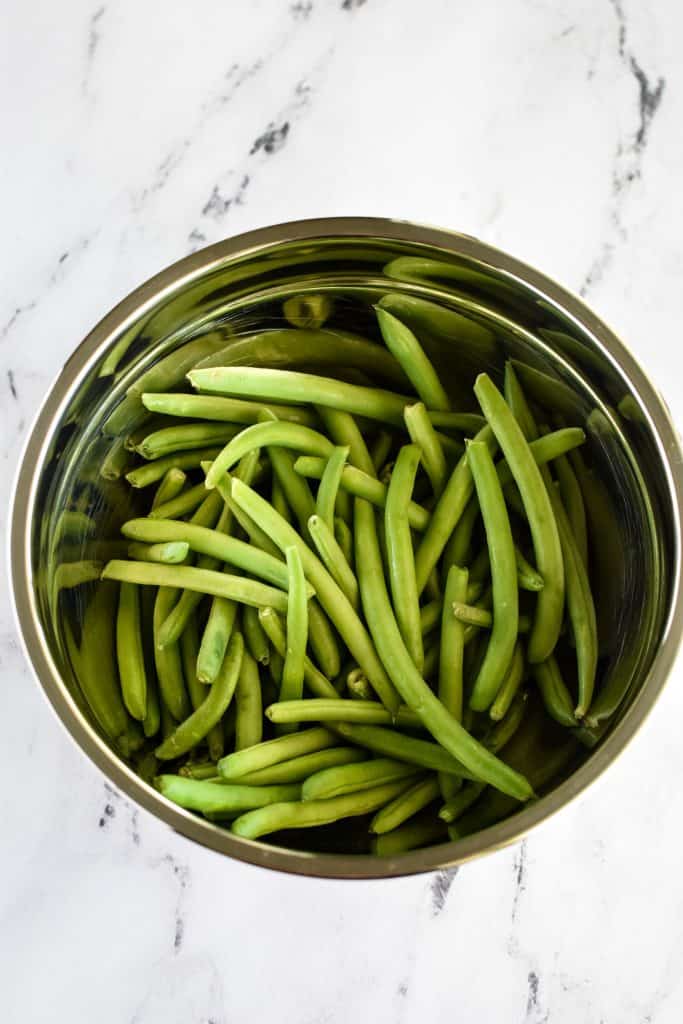 overhead of raw green beans in a mixing bowl.