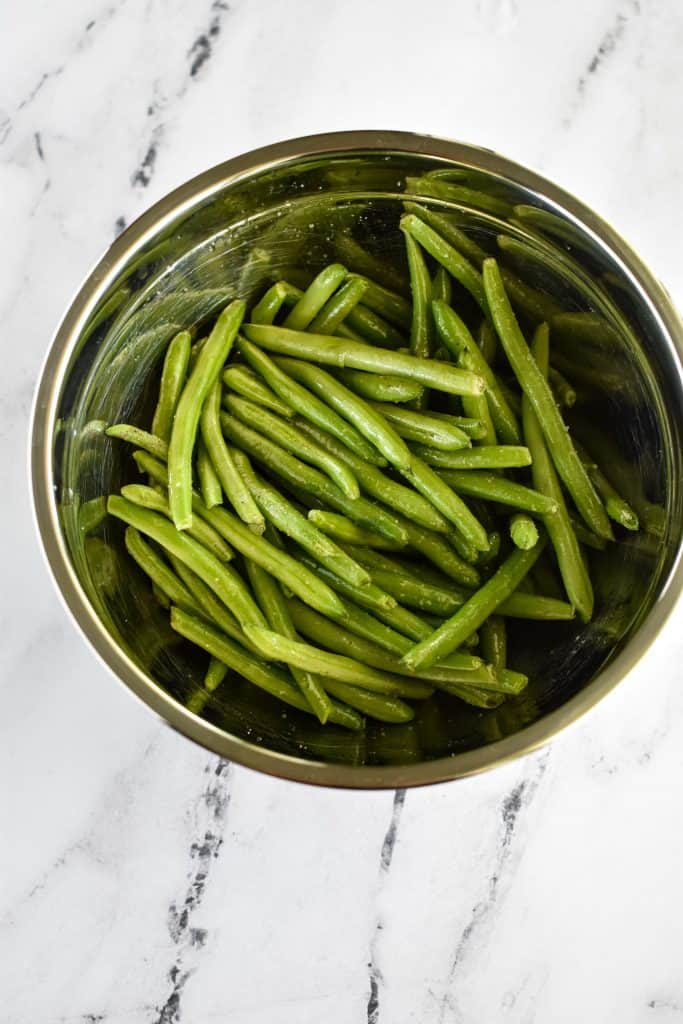 overhead of raw green beans tossed with oil, salt and pepper.