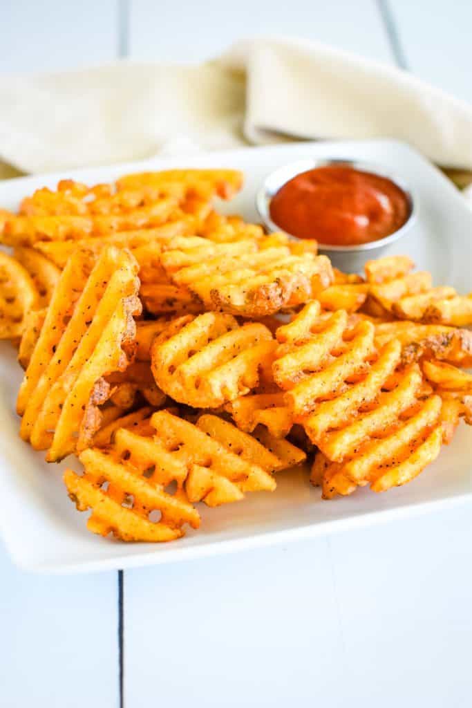 front view of fries on white plate with ketchup.