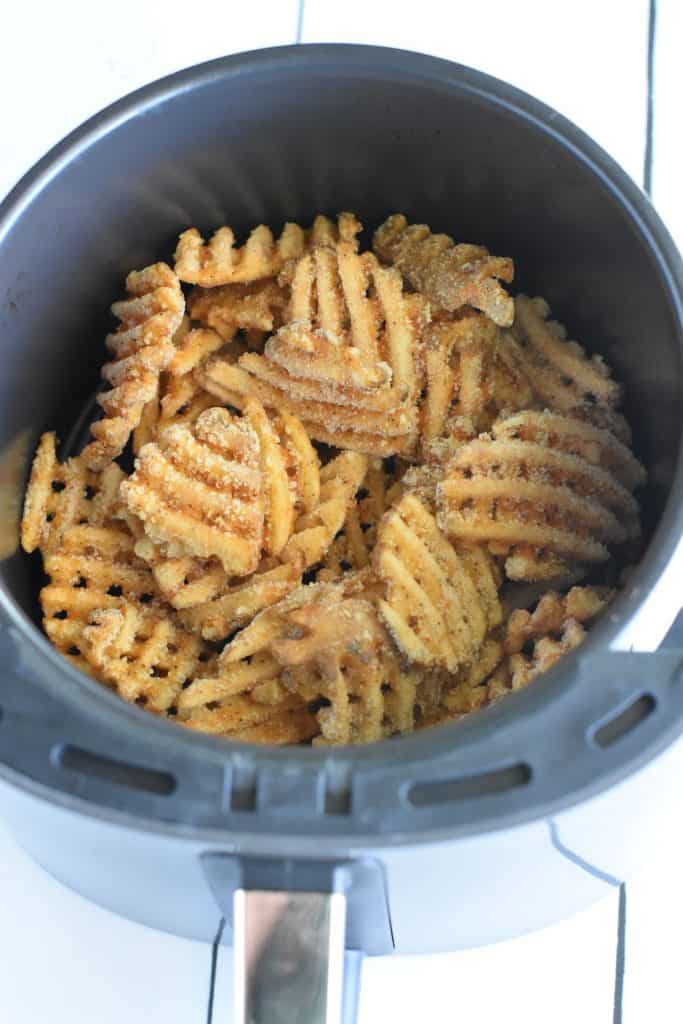 overhead of frozen waffle fries in air fryer before cooking.